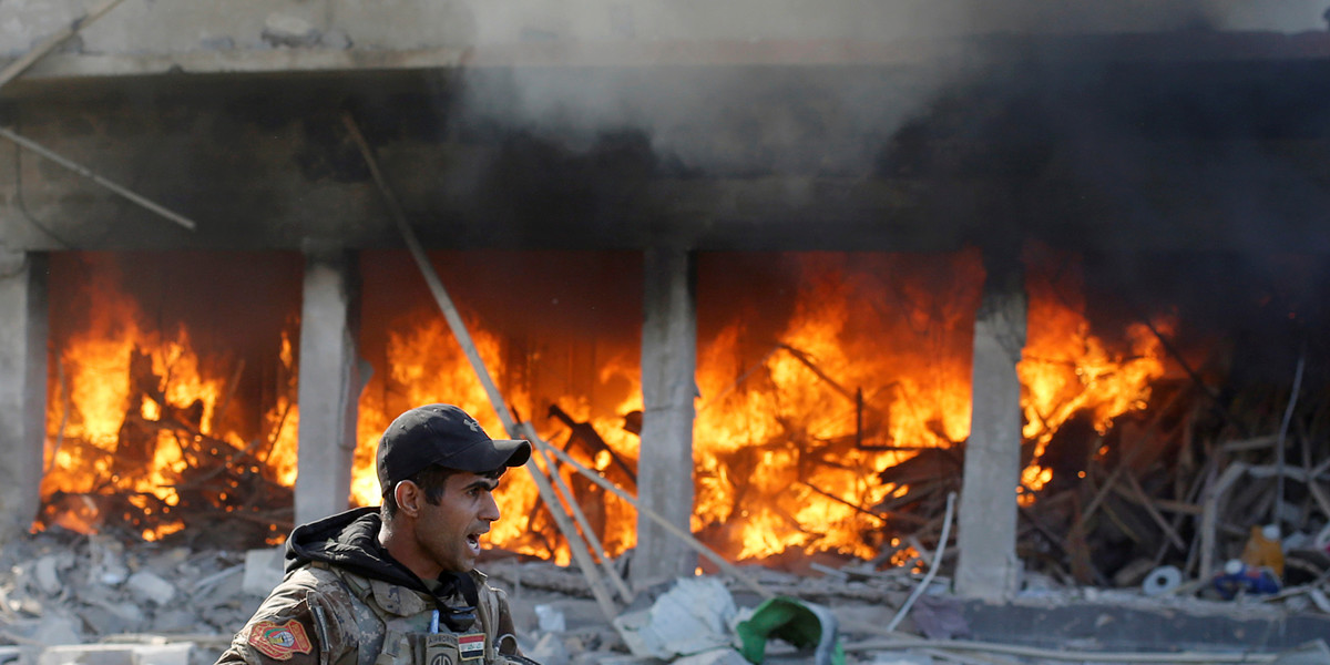 An Iraqi special-forces soldier standing in front of a burning house after an ISIS suicide car-bomb attack in Mosul on November 19.