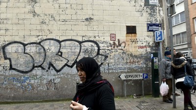 A woman passes close to the house where Salah Abdeslam was arrested after a shootout with police in 