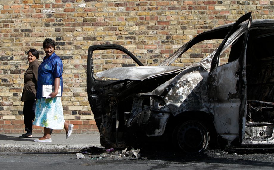 Two women passing a burned-out van on August 9, 2011, after riots and looting in Hackney.