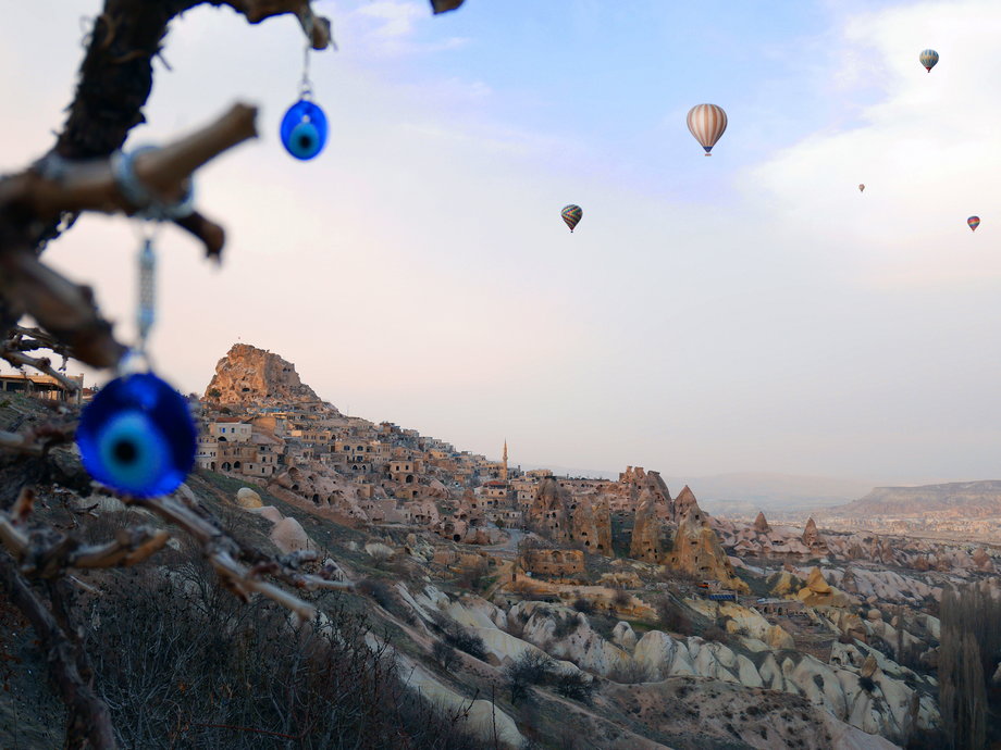 Starożytne miasto Uchisar z zaklęciami złego oka na pierwszym planie i balonami na ogrzane powietrze w tle, Kapadocja, Turcja