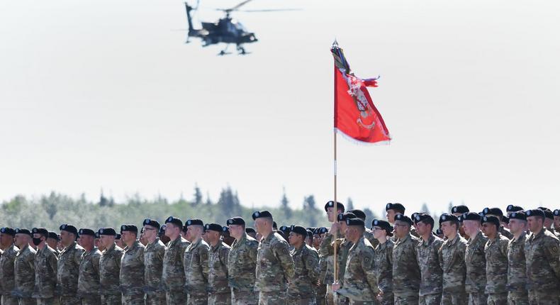 An AH-64 Apache helicopter flies over soldiers during the activation ceremony for the 11th Airborne Division, at Fort Wainwright, June 6, 2022.