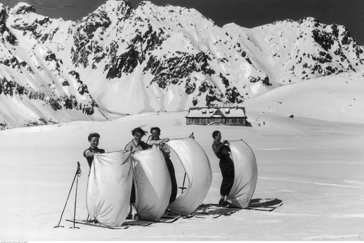 Narciarze podczas jazdy na nartach z przytwierdzonym żaglem na zamarzniętym jeziorze