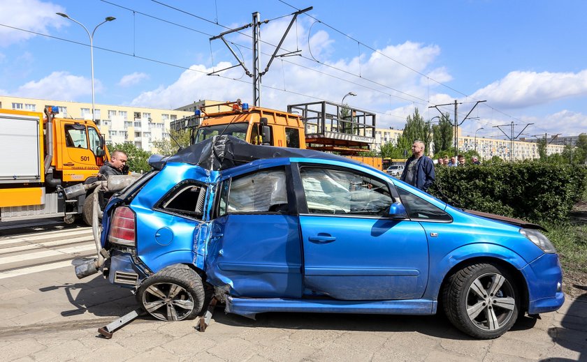 Samochód zaklinowany pomiędzy tramwajem a słupem. W środku ciężarna kobieta i dziecko