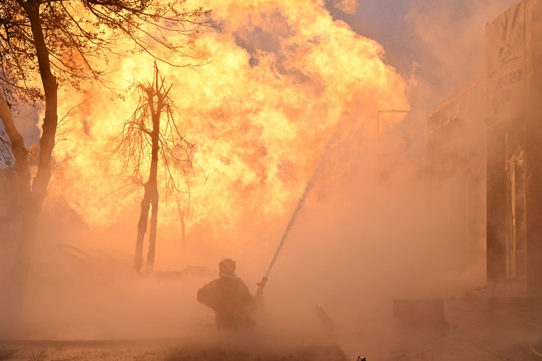 Ukraińscy strażacy próbujący ugasić pożar po uderzeniu rakietowym w Kijowie, 2 stycznia 2024 r.