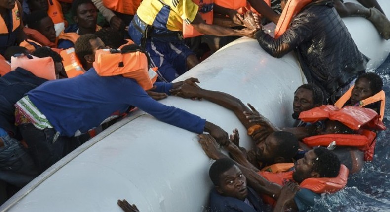 Migrants cling to a boat during a rescue operation off the Libyan coast in November 2016