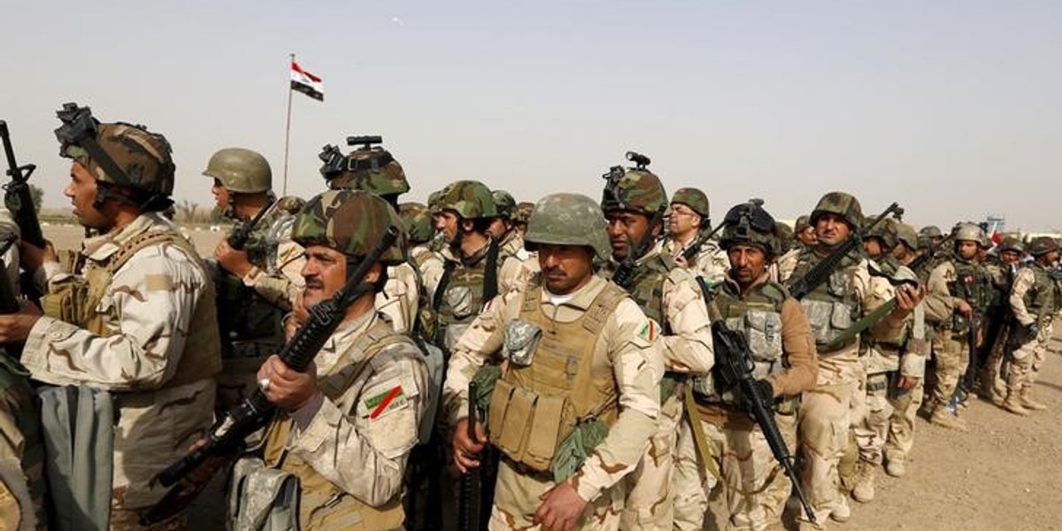 Iraqi security forces wait at an army base in Baghdad for vehicles traveling to Mosul to fight ISIS militants.