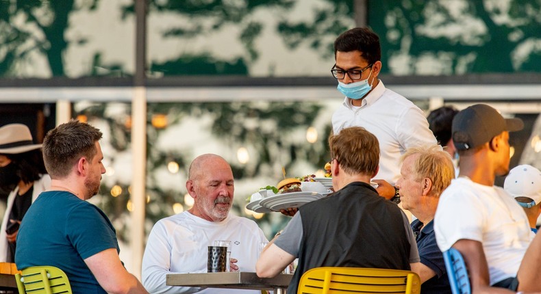 Waiters wear face masks as they serve people sitting in outside seating at the P.J. Clarke's restaurant at Rockefeller Park in lower Manhattan during the fourth phase of the coronavirus reopening on Aug. 05, 2020 in New York, New York.