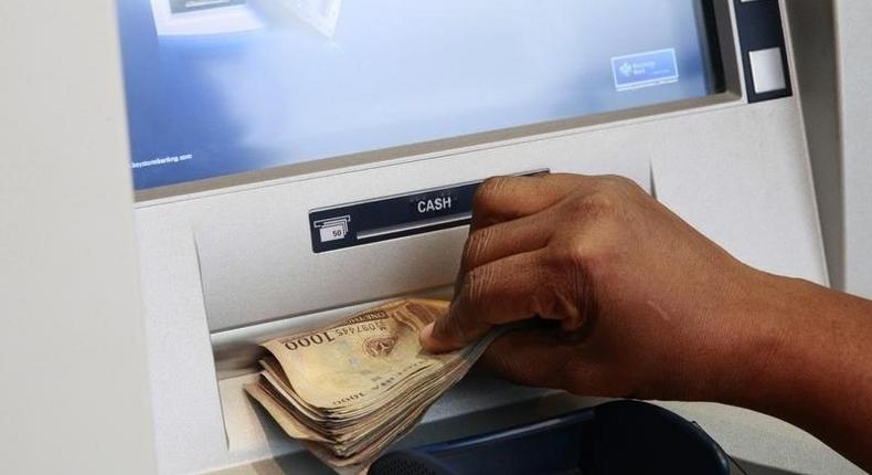 A woman takes Nigerian Naira from a bank's automated teller machine (ATM) in Ikeja district in the commercial capital Lagos November 12, 2014. 