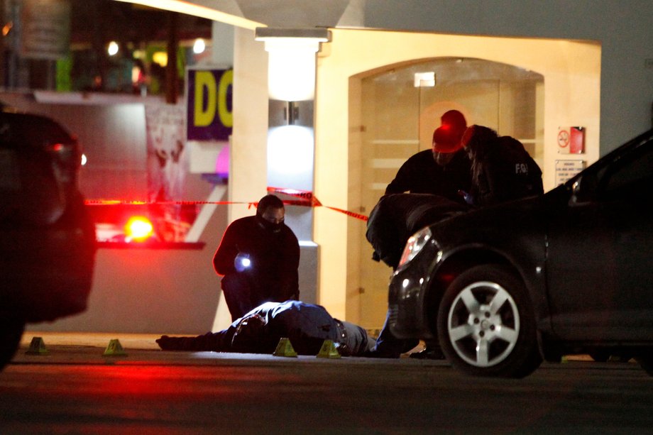 Forensic technicians inspect a body after unknown assailants gunned down two people leaving a restaurant in Ciudad Juarez, Mexico, January 17, 2017.