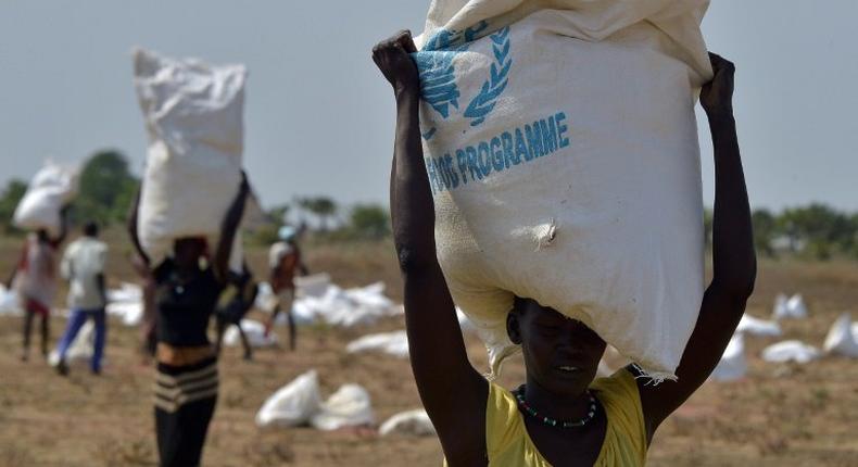 A woman carries a sack of food after a World Food Programme aid drop in South Sudan in February 2015