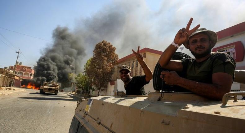 Members of the Iraqi forces flash the victory sign from a tank as they advance through Tal Afar on August 26, 2017