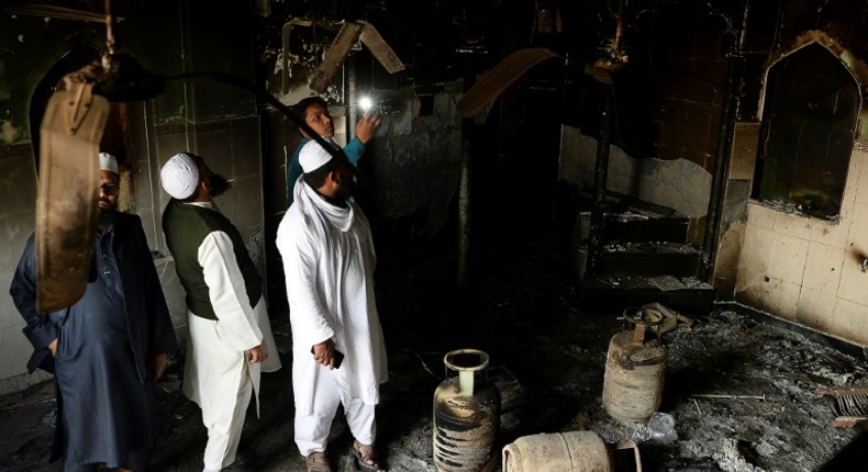 Muslim men check the interior of a partially burnt mosque on March 1, 2020 after communal riots in New Delhi