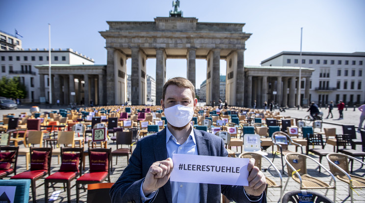 "Üres székek” felíratot tart az egyik demonstráló a berlini Brandenburgi kapu előtt, hiányolva a kormány könnyítő intézkedéseit /Fotó: MTI-EPA