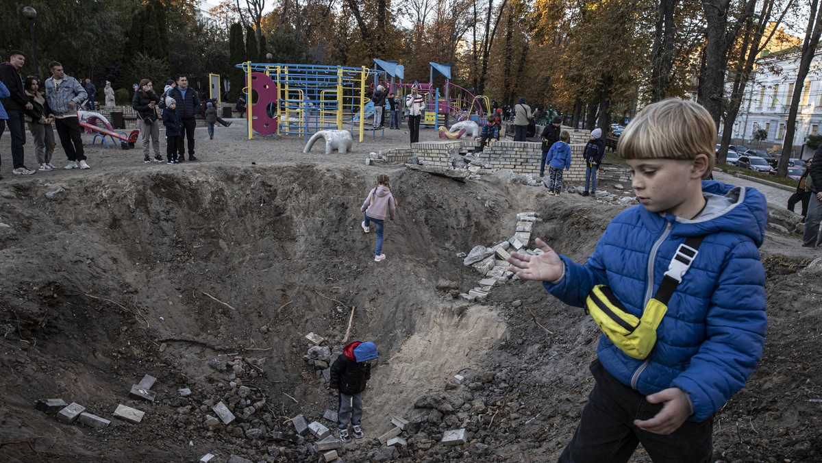 Dzieci bawią się w kraterach po pociskach w Kijowie, 16 października 2022 r.