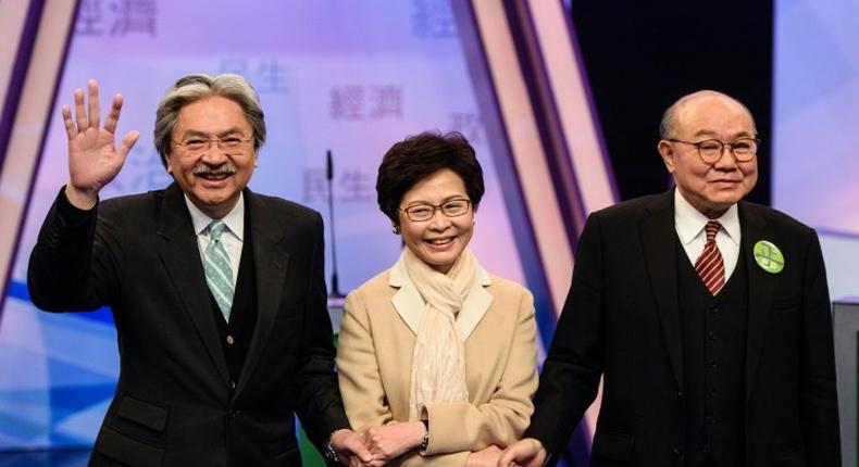 Hong Kong's three leadership candidates (L-R) John Tsang, Carrie Lam and ex-judge Woo Kwok-hing join hands in a Hong Kong TV studio before facing off in their first televised debate on March 14, 2017