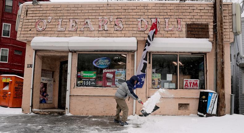 A store employee clears snow from the front of a deli in Yonkers, New York, on March 14.