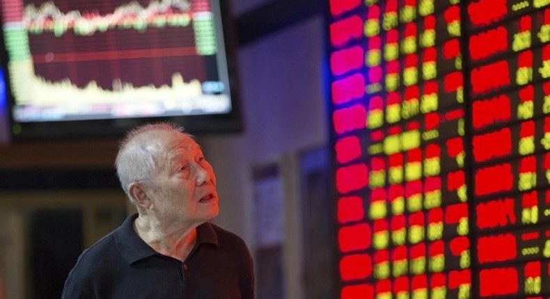 An investor walks past an electronic board showing stock information at a brokerage house in Nanjing, Jiangsu province, China, September 22, 2015. REUTERS/Stringer