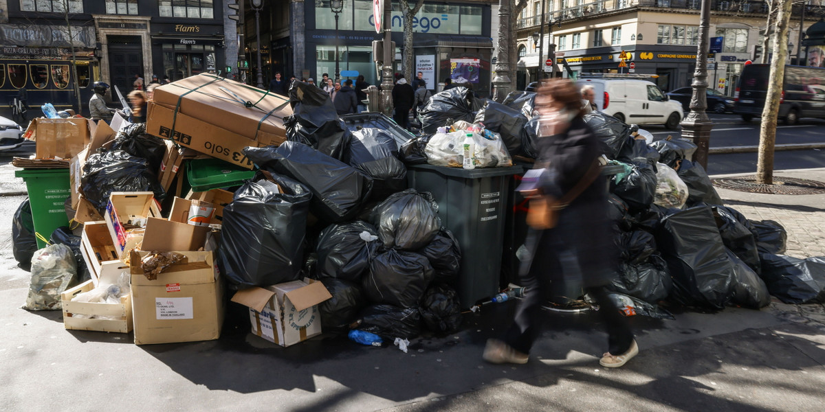 Ludzie przechodzą obok pojemników przepełnionych śmieciami w Paryżu, Francja, 14 marca 2023 r. Śmieciarze przyłączyli się do masowych strajków we Francji przeciwko rządowym planom reformy emerytalnej.