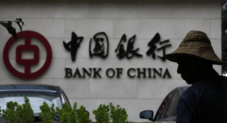 A man is silhouetted in front of a Bank of China's logo at its branch office in Beijing July 14, 2014.   REUTERS/Kim Kyung-Hoon