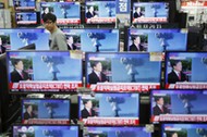 A sales assistant watches TV sets broadcasting a news report on North Korea's nuclear test, in Seoul