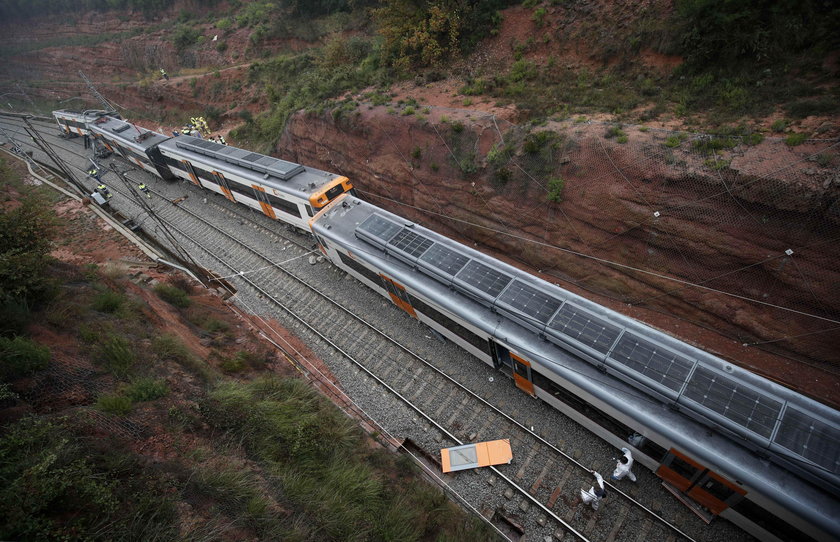 Firefighters, police and other officials survey the scene after a commuter train derailed between Te