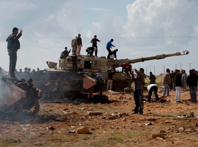 Rebelianci na spalonym czołgu, należącym do sił Muammara Kadafiego, zniszczonym podczas francuskiego nalotu 25 km od Bengazi