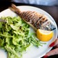 Grilled whole sea bream served with rocket salad and lemon