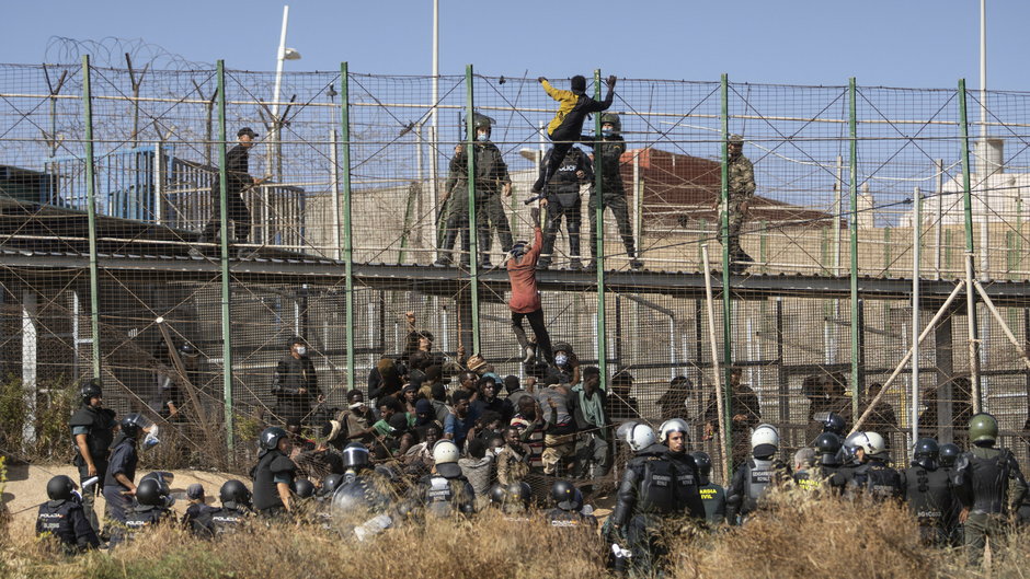 Migranci próbują przedostać się przez płot graniczny między Hiszpanią a Marokiem, 24 czerwca 2022 r.