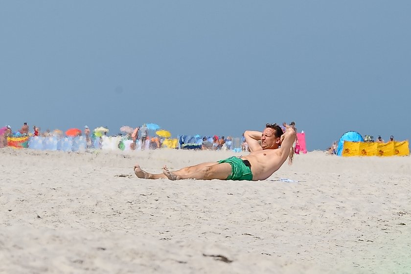 Radosław Sikorski na plaży ćwiczy brzuszki 