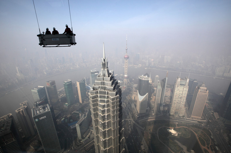 Widok na Szanghaj z najwyższych pięter budynku Shanghai World Financial Center. Na pierwszym planie platforma z pracownikami przygotowującymi się do mycia okien w wieżowcu. Gospodarka Chin wzrosła w III kwartale 2013 roku o 7,3 proc. Fot. Tomohiro Ohsumi, Bloomberg's Best Photos 2013.