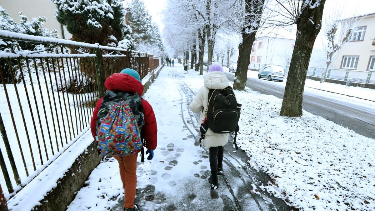 Deti idú do školy po rannom snežení.