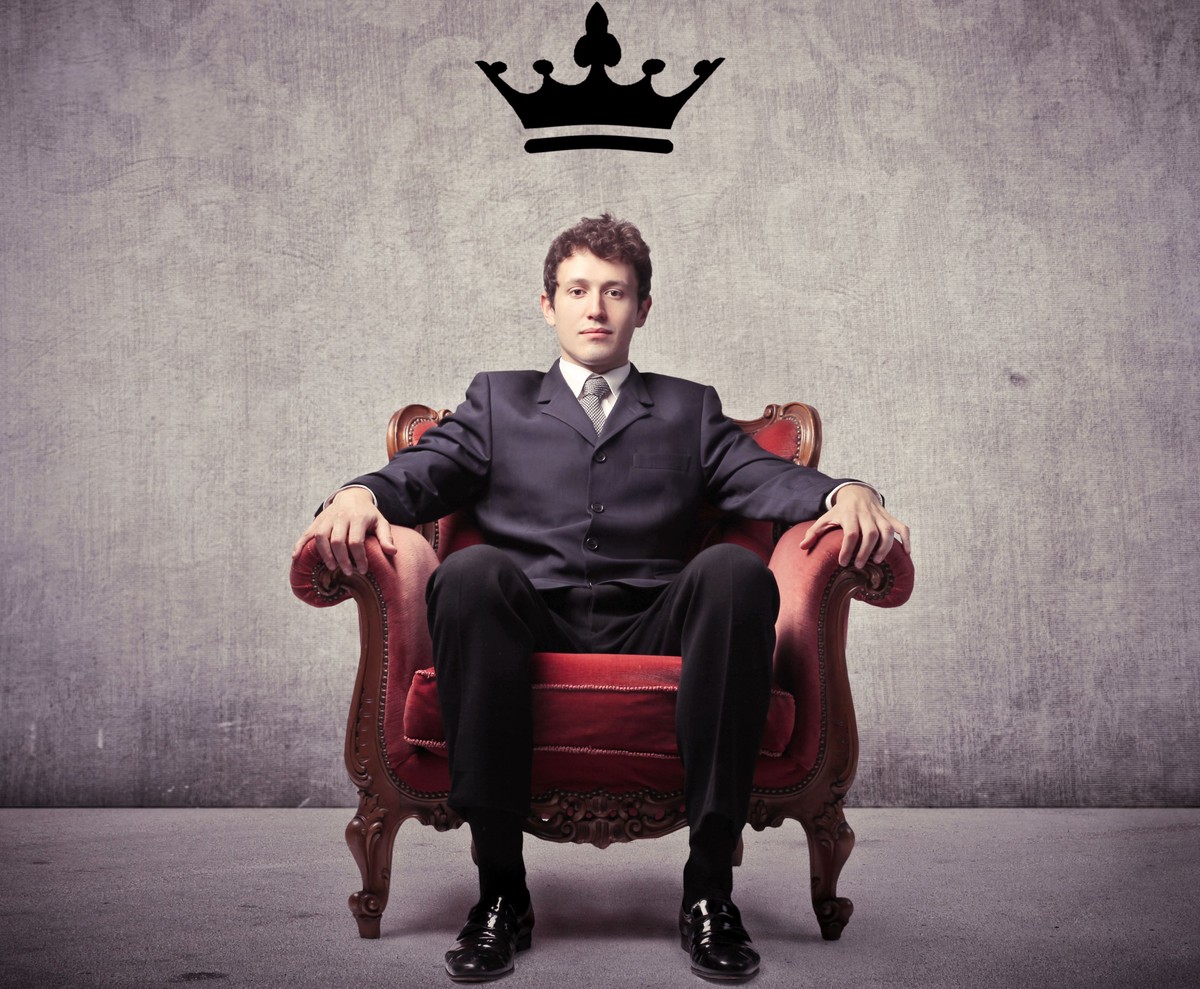 Mężczyzna siedzący na tronie, na ścianie namalowana korona