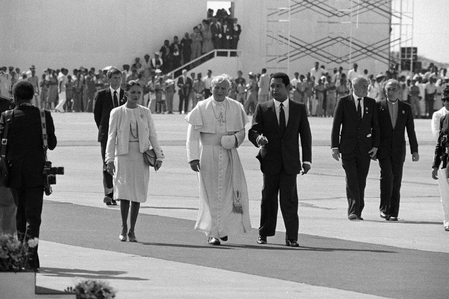 Papież Jan Paweł II spaceruje z haitańskim prezydentem Jean-Claude Duvalier i jego żoną Michelle podczas otwarcia ceremonii na lotnisku Port-au-Prince na Haiti, 1983 r.