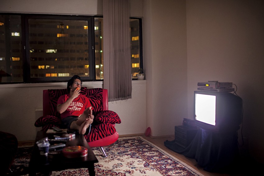 Amir (25), koji živi sam, sedi u dnevnoj sobi i gleda televiziju (FOTO: Fabrica)