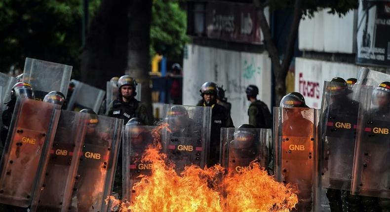 Members of Venezuela's National Guard use their shields to form a barrier from a fire during clashes with anti-government demonstrators in Caracas