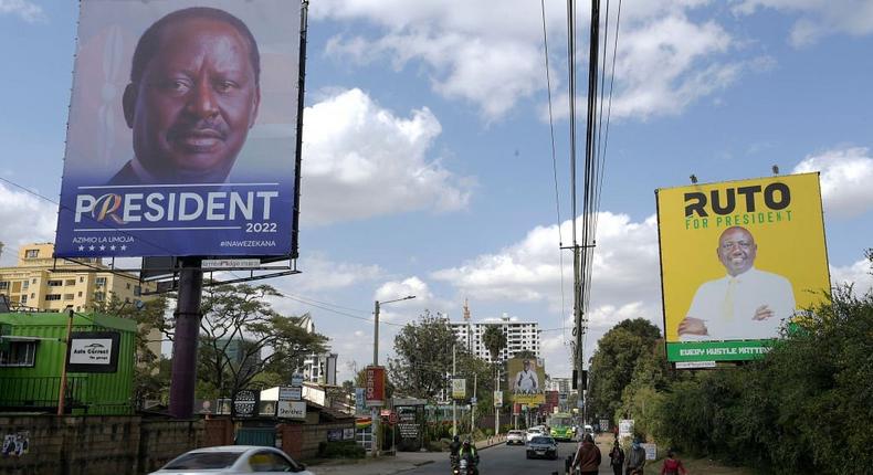 Pedestrians and motorists are seen next to campaign posters for Presidential candidates for Azimio La Umoja (Aspiration to Unite) Raila Odinga (L) and United Democratic Alliance (UDA) William Ruto, in Nairobi on June 30, 2022. -  (Photo by SIMON MAINA/AFP via Getty Images)