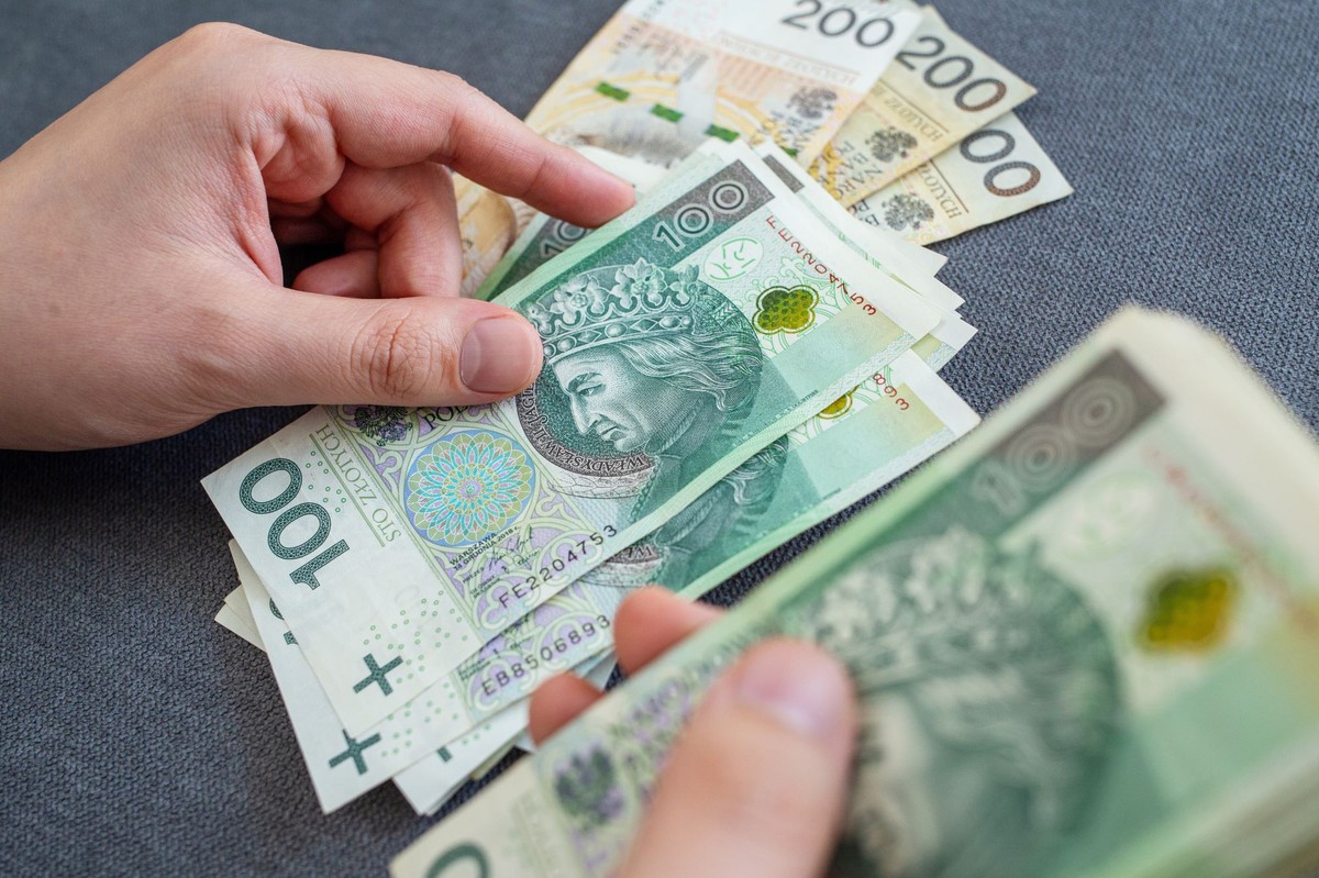 Mężczyzna liczy pieniądze - banknoty 100 i 200 zł