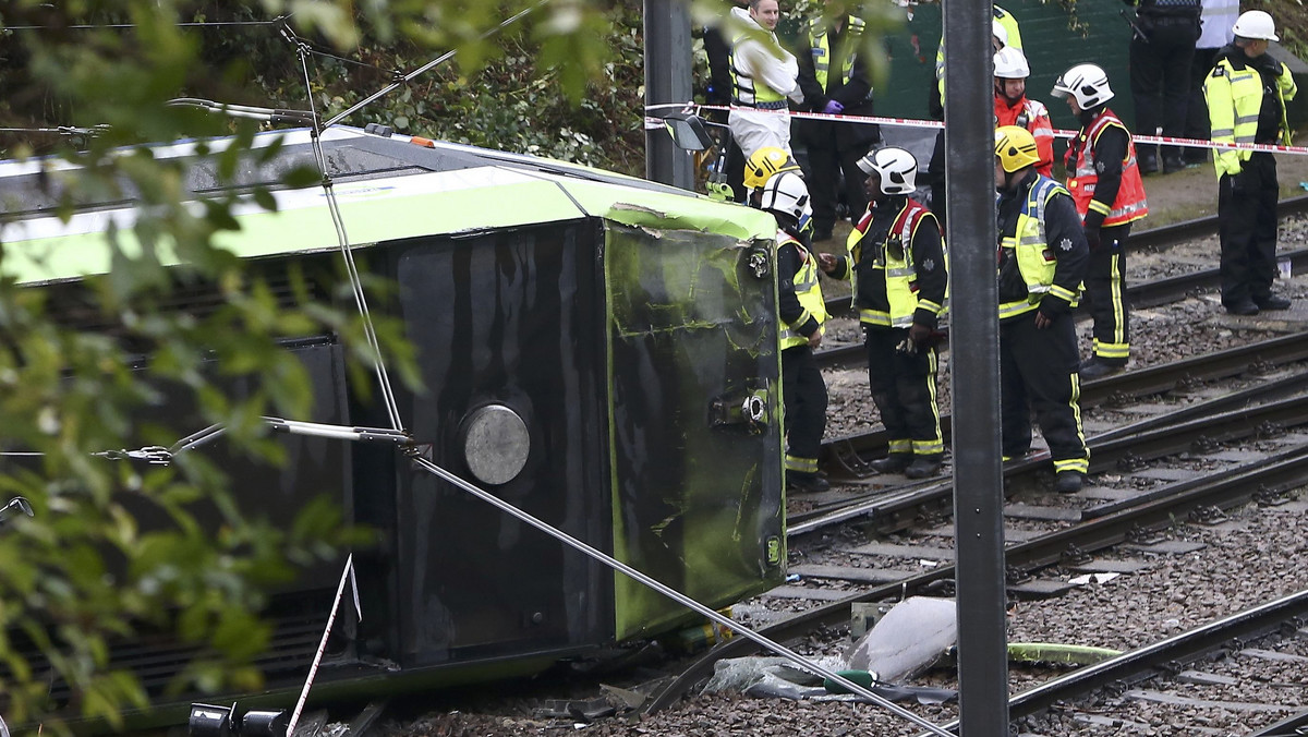 Members of the emergency services work next to a tram after it overturned injuring and trapping some passengers in Croydon, south London