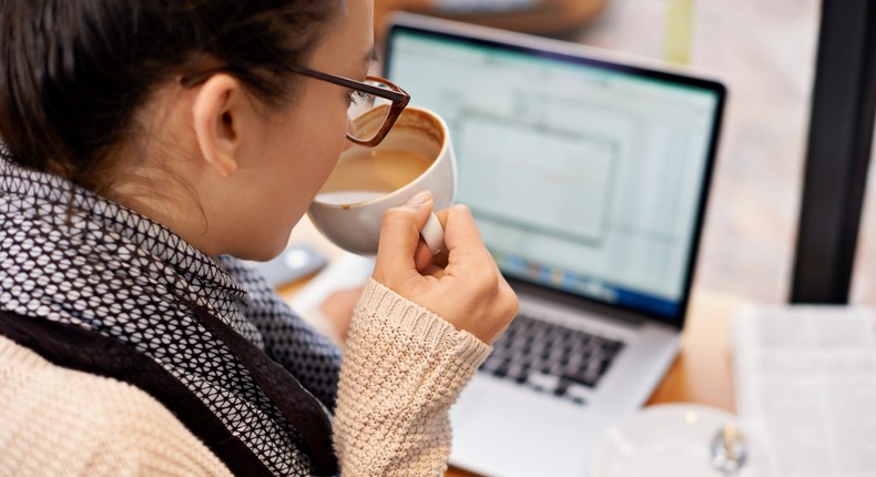 Woman working at desk drinking coffee and downloading files