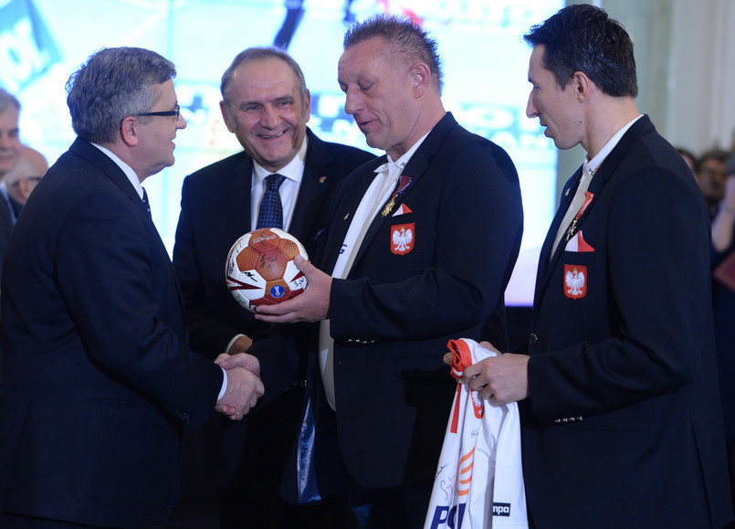 Prezydent Bronisław Komorowski (L) dobiera z rąk trenera Michaela Bieglera (2-P) piłkę i koszulkę reprezentacji podczas spotkania z medalistami mistrzostw świata w piłce ręcznej mężczyzn