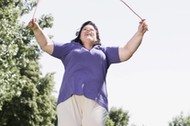 overweight woman skipping in park