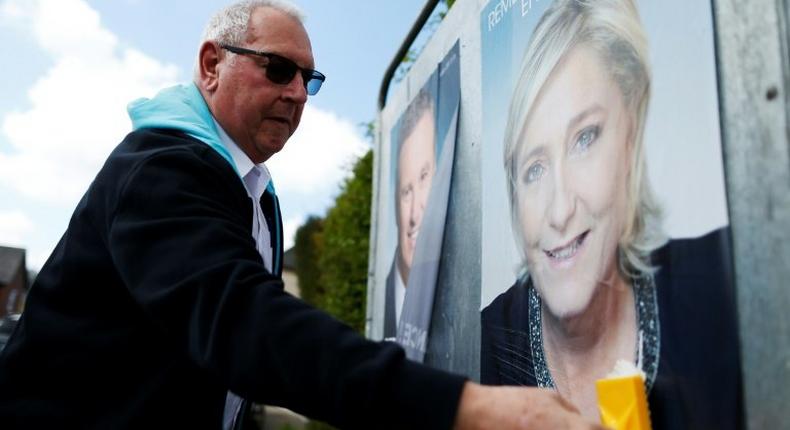 A man puts up a campaign poster for French presidential election candidate Marine Le Pen in the city of Dieppe, northwestern France, on April 14, 2017