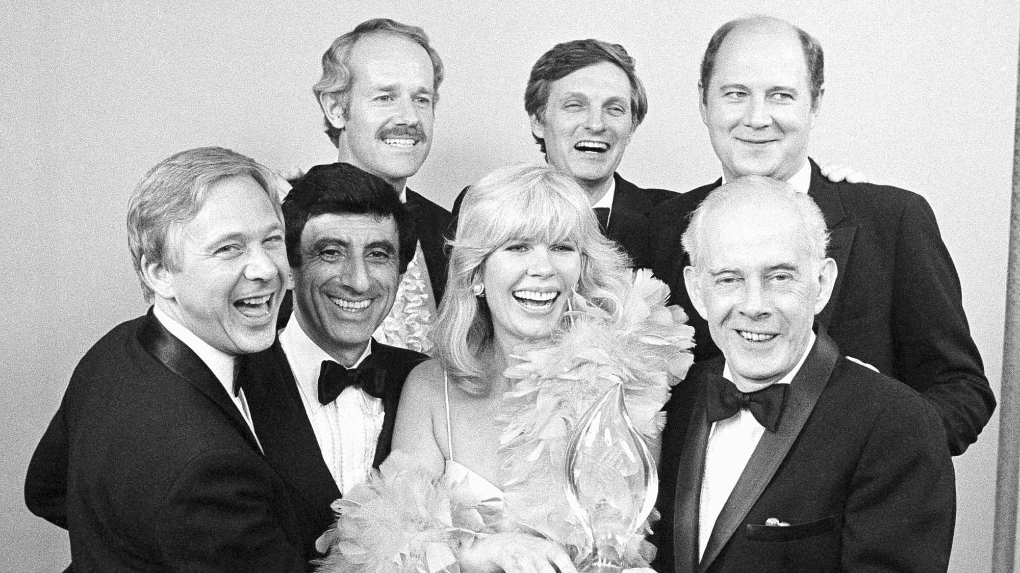 Herci zo seriálu M.A.S.H. : zľava William Christopher, Jamie Farr, Loretta Swit a Henry Morgan, zadný rad zľava, Mike Farrell, Alan Alda a William Ogden Stiers.