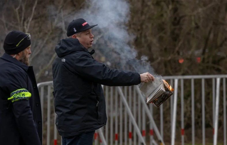 Rasmus Paludan, lider skrajnie prawicowej partii Hard Deal, trzyma płonący Koran przed ambasadą Turcji w Sztokholmie, 21 stycznia 2023 r.