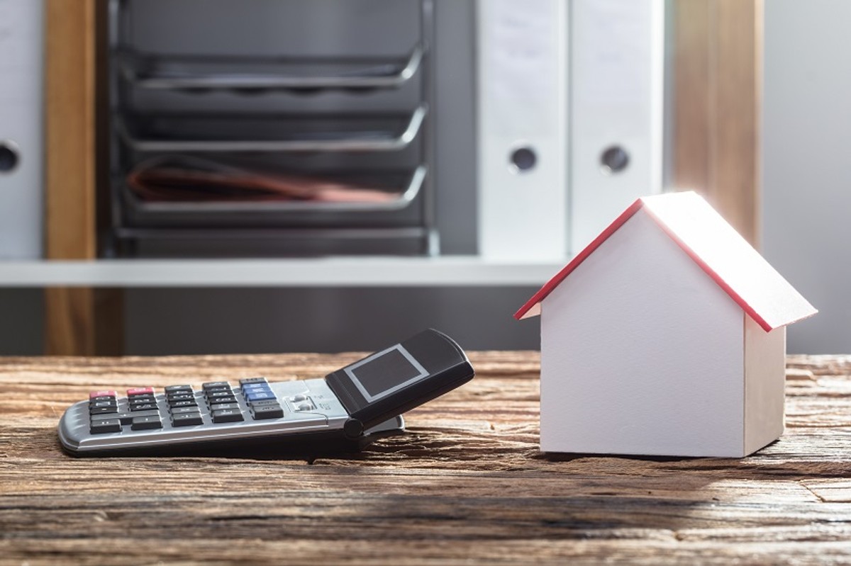 Close-up Of House Model And Calculator On Wooden Desk