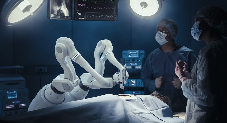 Stock image of two surgeons observing high-precision programmable automated robot arms operating on a patient. For illustration purposes only.Getty Images