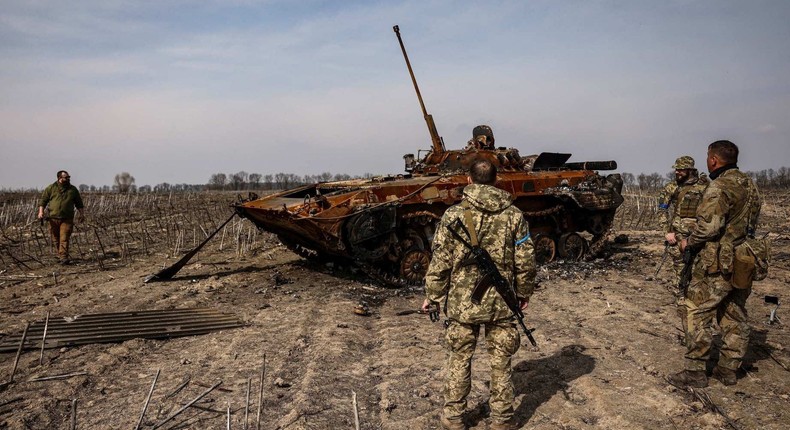 Ukrainian soldiers stand by a burnt Russian tank on the outskirts of Kyiv, on March 31, 2022.