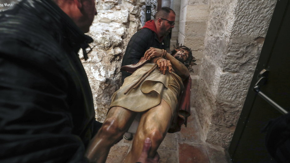 Pracownicy kościoła przenoszą zniszczoną figurę Jezusa