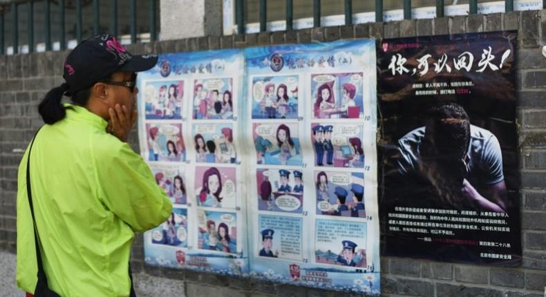 A woman looks at a propaganda cartoon warning local residents about foreign spies, in an alley in Beijing on May 23, 2017