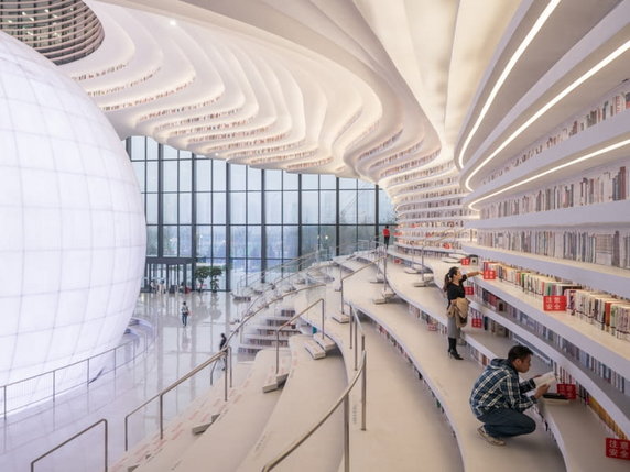 Biblioteka Binhai w Tianjin. W 2017 r. świat zachwycił się, kiedy zdjęcia chińskiej biblioteki obiegły Internet. Zaprojektowana przez holenderską firmę MVRDV biblioteka, pośrodku audytorium zawiera ogromną świetlistą kulę (zwaną "Okiem"), sklepione łuki przypominające katedrę i pofalowane półki od podłogi do sufitu. Jest tylko jeden haczyk: na najwyższych, niedostępnych półkach nie ma książek — zamiast tego są na nich aluminiowe płyty z nadrukowanymi ich obrazami.